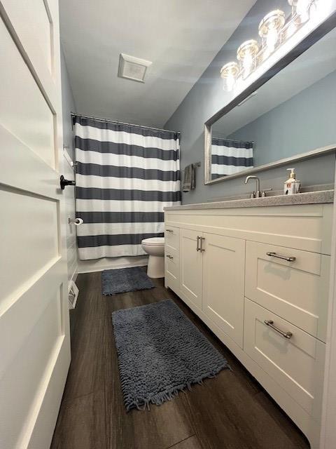 bathroom with hardwood / wood-style flooring, vanity, toilet, and a shower with shower curtain