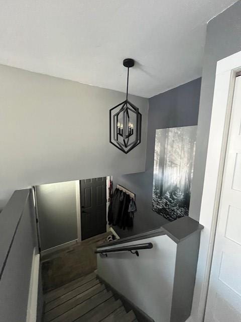 staircase with wood-type flooring and an inviting chandelier