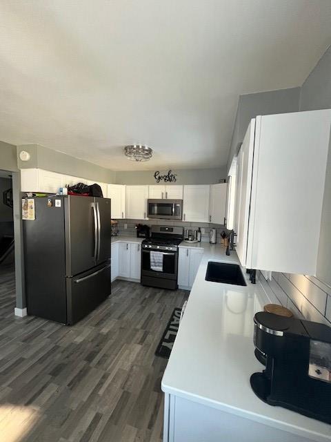 kitchen with appliances with stainless steel finishes, sink, white cabinets, and dark hardwood / wood-style flooring