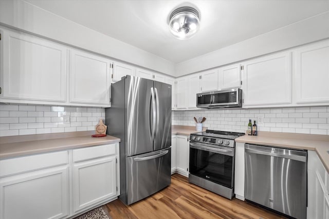 kitchen with appliances with stainless steel finishes, light wood-type flooring, decorative backsplash, and white cabinets