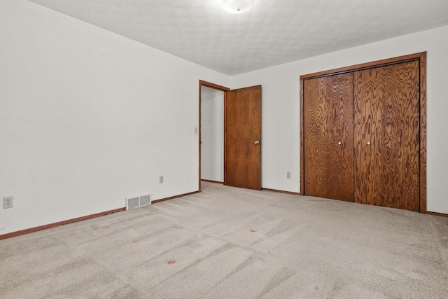 unfurnished bedroom with light carpet and a closet