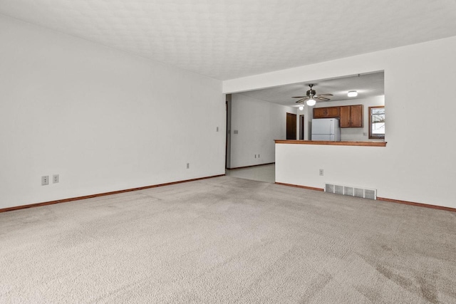 unfurnished living room with ceiling fan, light carpet, and a textured ceiling