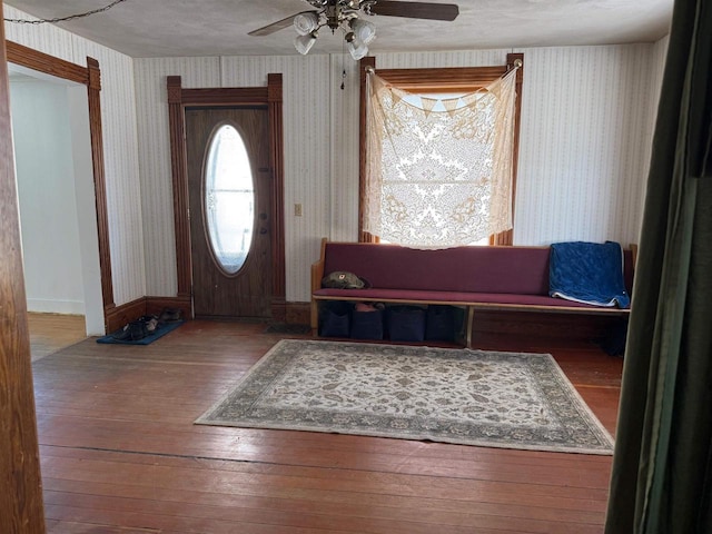 foyer featuring baseboards, ceiling fan, wood finished floors, and wallpapered walls