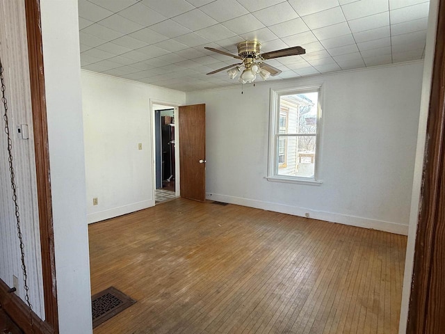 spare room featuring baseboards, visible vents, wood finished floors, and ornamental molding