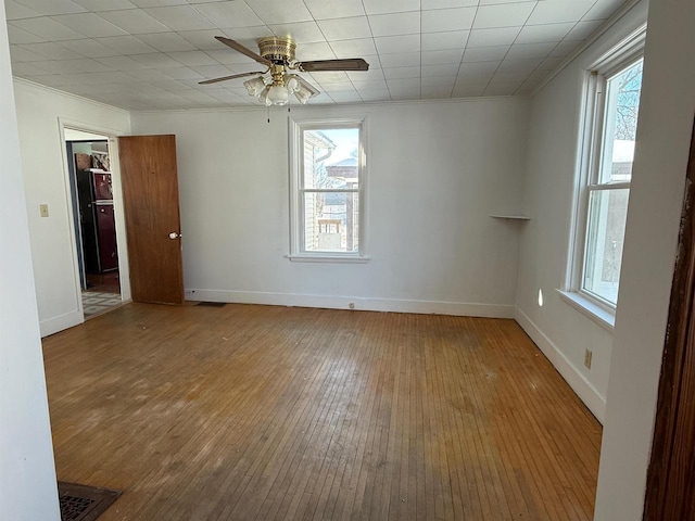 empty room with a wealth of natural light, baseboards, and wood finished floors