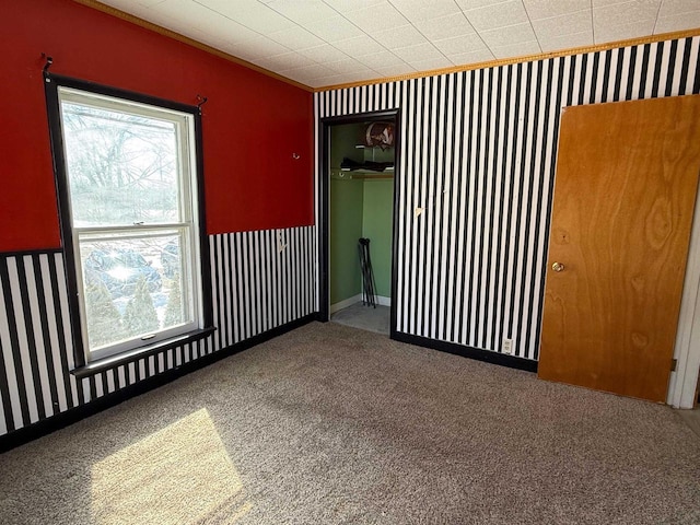 unfurnished room with baseboards, carpet, and wallpapered walls