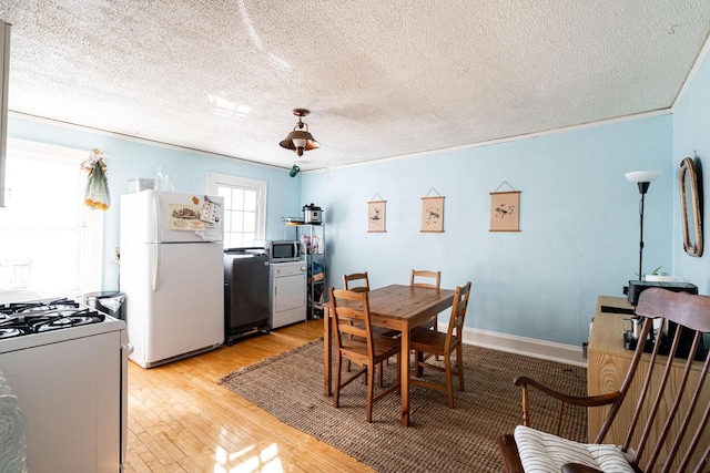 dining space featuring ornamental molding, a textured ceiling, and light wood-type flooring