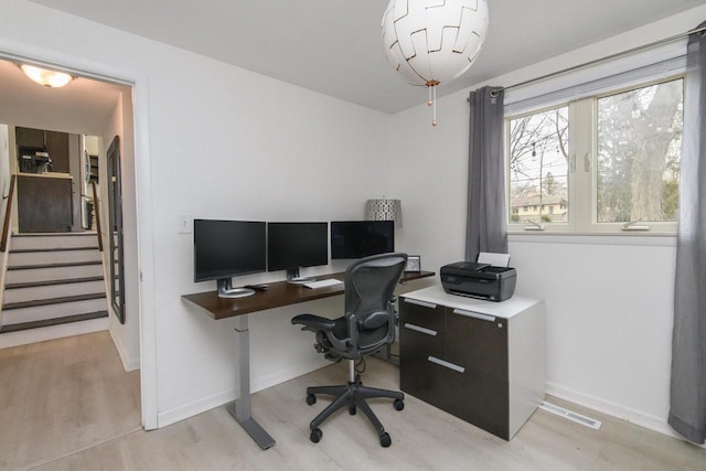 office area with light wood-style floors, visible vents, and baseboards