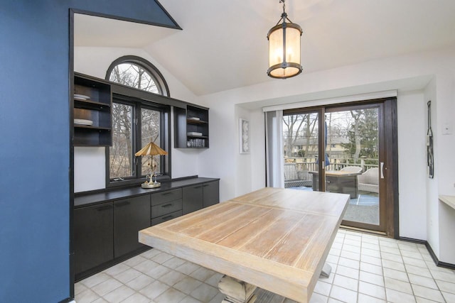 dining area featuring baseboards, vaulted ceiling, and light tile patterned flooring