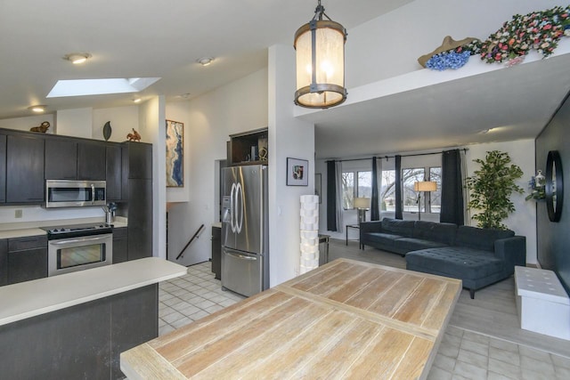 kitchen featuring light tile patterned floors, vaulted ceiling with skylight, stainless steel appliances, and light countertops