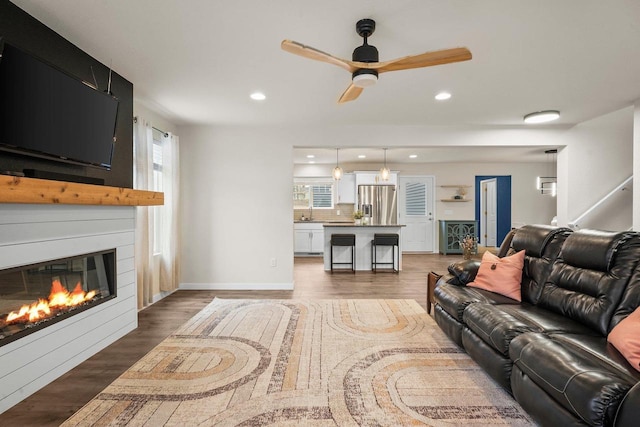 living room with a ceiling fan, recessed lighting, a large fireplace, and wood finished floors