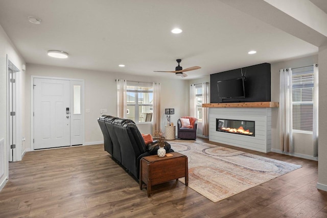 living area featuring a fireplace, recessed lighting, ceiling fan, wood finished floors, and baseboards