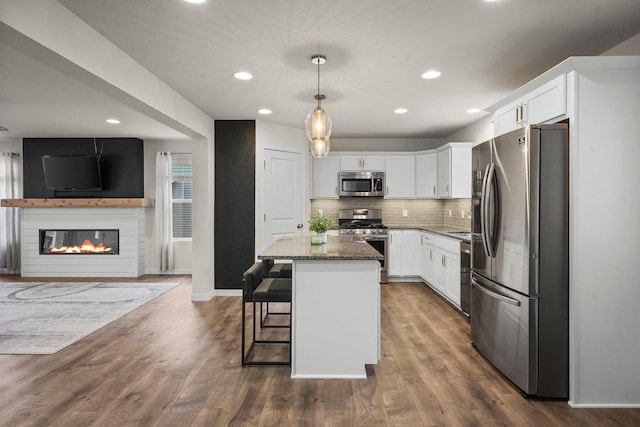 kitchen featuring dark wood-style floors, stainless steel appliances, decorative backsplash, open floor plan, and white cabinets