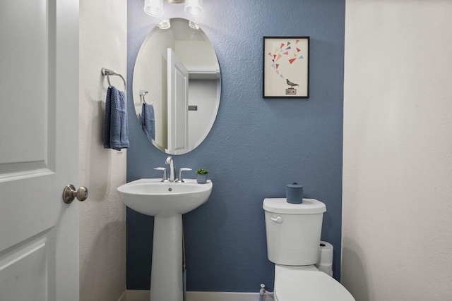 bathroom featuring toilet and a textured wall