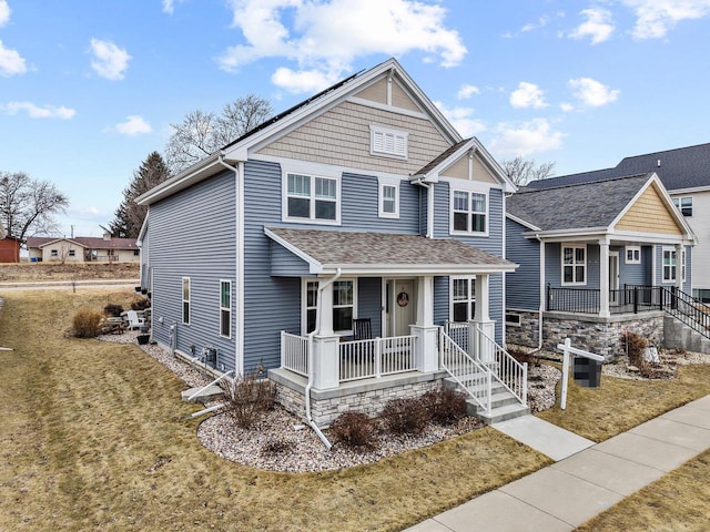 view of front of property featuring covered porch, roof with shingles, and roof mounted solar panels