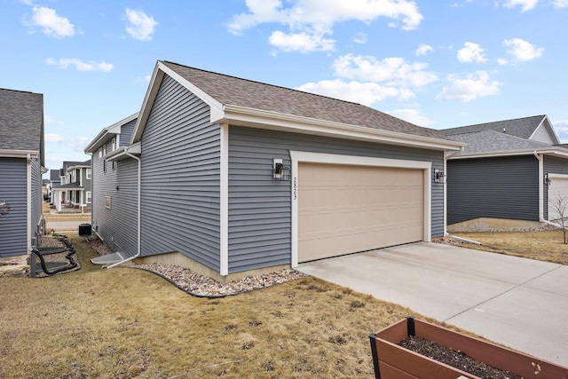 view of home's exterior featuring a garden, a lawn, concrete driveway, roof with shingles, and an attached garage