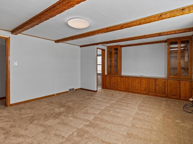 carpeted empty room with beamed ceiling