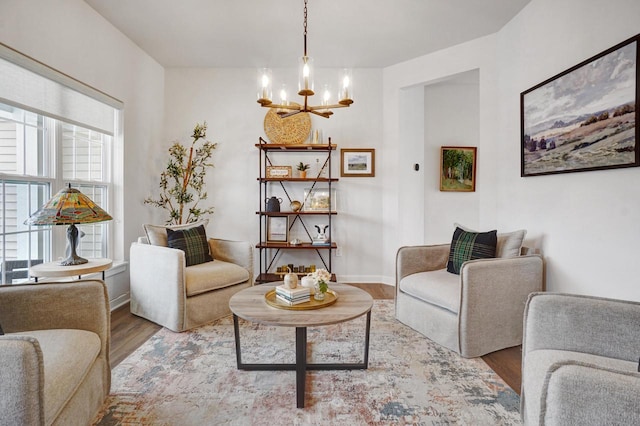 sitting room featuring baseboards, wood finished floors, and a notable chandelier