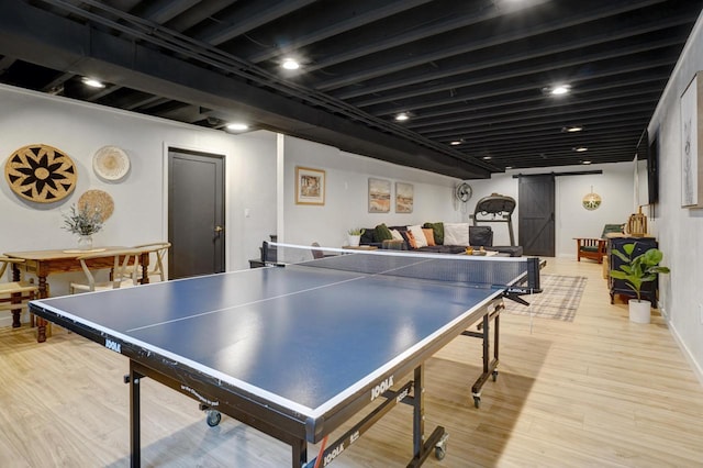 rec room featuring light wood finished floors and a barn door