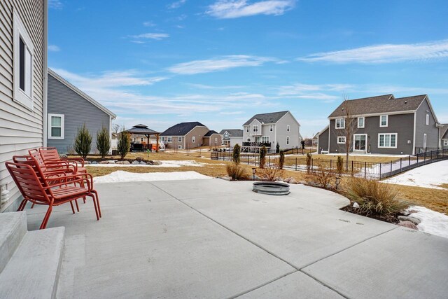 snow covered patio featuring a gazebo, fence, and a residential view