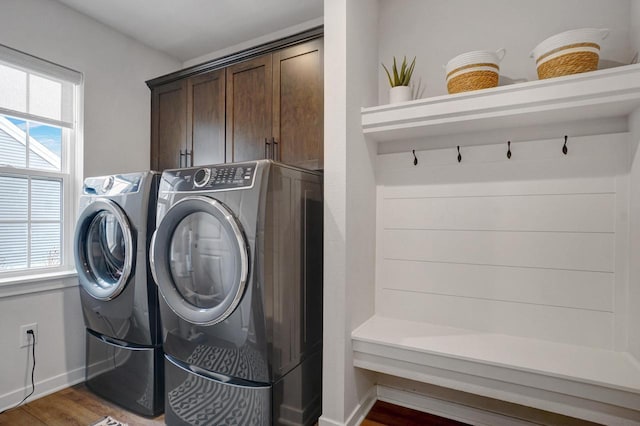 laundry room featuring dark wood-style flooring, washing machine and dryer, cabinet space, and baseboards