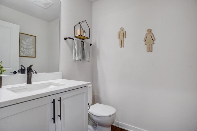 half bath featuring wood finished floors, vanity, toilet, and baseboards