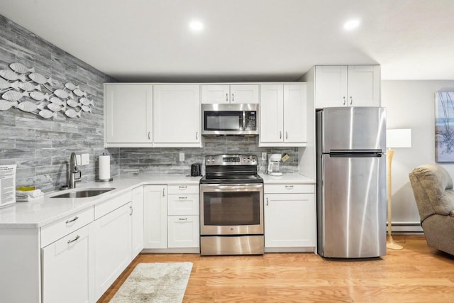 kitchen with white cabinetry, stainless steel appliances, light hardwood / wood-style flooring, and sink