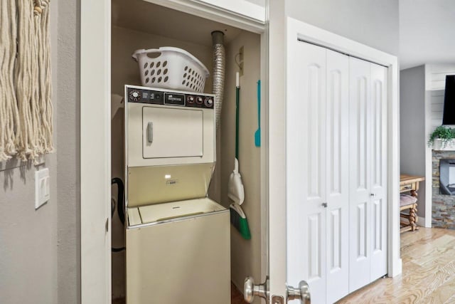 laundry area with stacked washing maching and dryer and light hardwood / wood-style floors