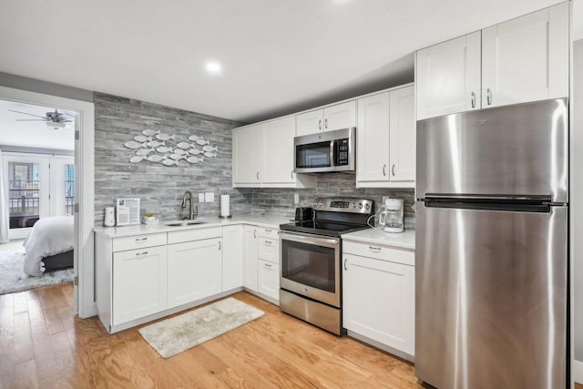 kitchen with sink, stainless steel appliances, white cabinetry, and tasteful backsplash