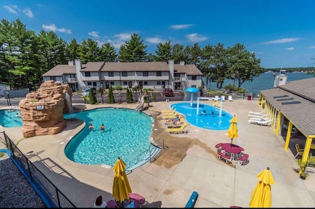 view of pool featuring pool water feature, a water view, and a patio area