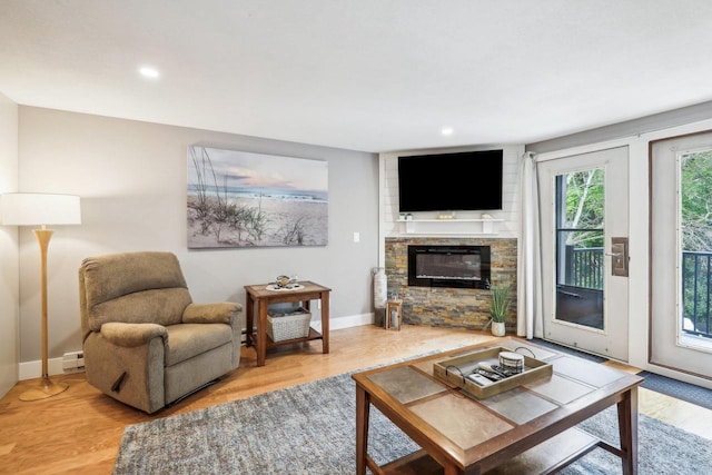 living room with a fireplace, light wood-type flooring, and baseboard heating