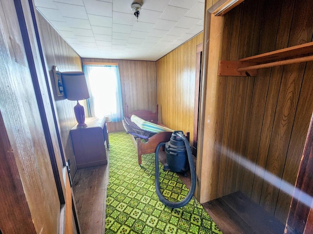 bedroom with dark hardwood / wood-style floors and wooden walls