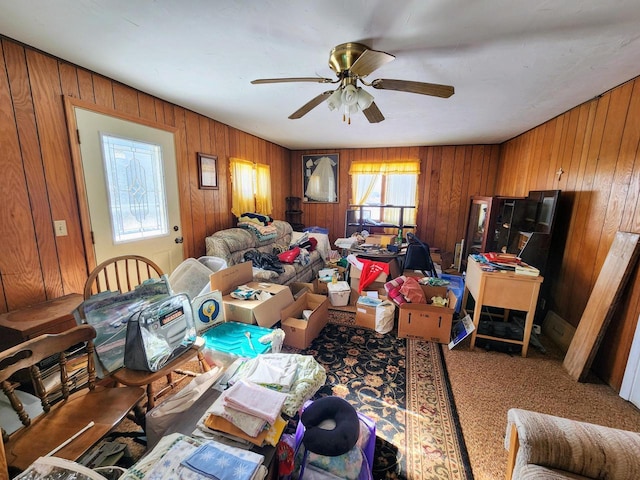 interior space with carpet, ceiling fan, and wood walls