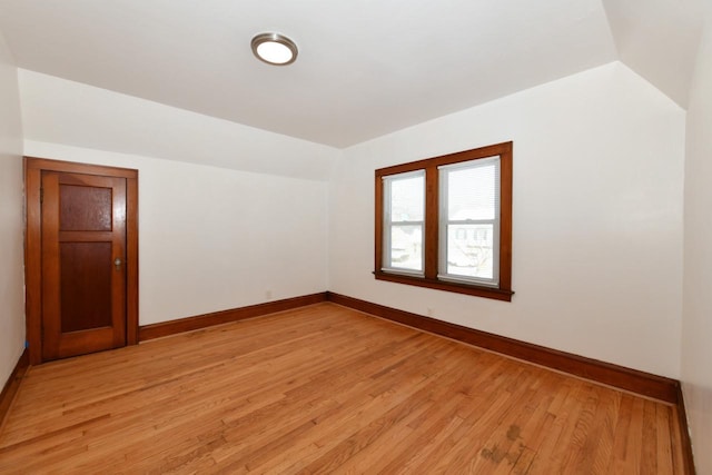 empty room featuring light wood-type flooring and vaulted ceiling