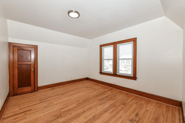 empty room with light wood-type flooring and vaulted ceiling