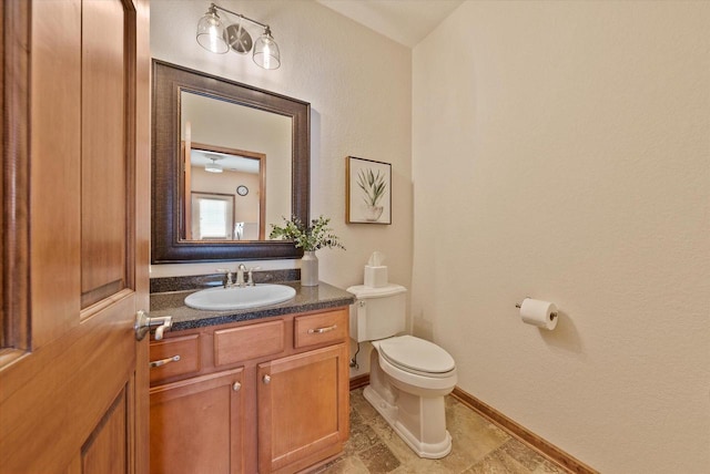 bathroom featuring toilet, vanity, and baseboards