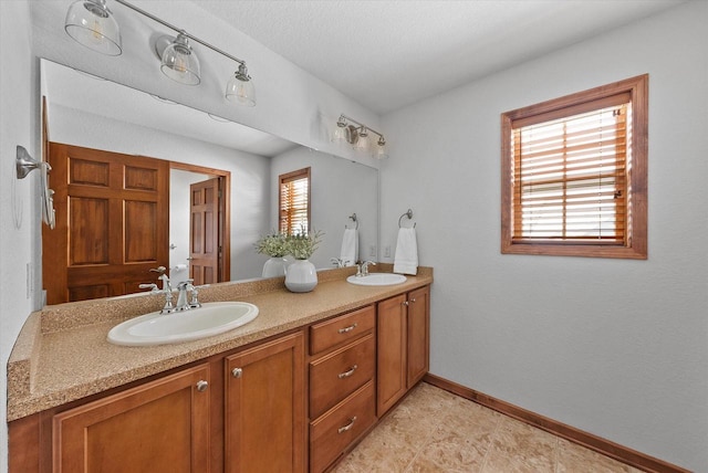 full bathroom featuring a sink, baseboards, and double vanity