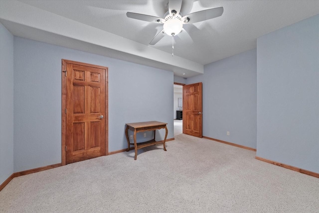 spare room featuring baseboards, a ceiling fan, and light colored carpet