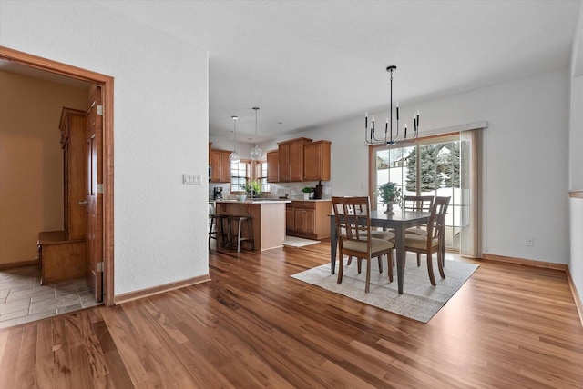 dining room featuring a notable chandelier, light wood-style flooring, and baseboards