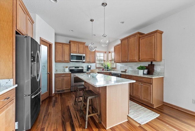 kitchen featuring decorative backsplash, dark wood-style floors, appliances with stainless steel finishes, a breakfast bar, and a center island