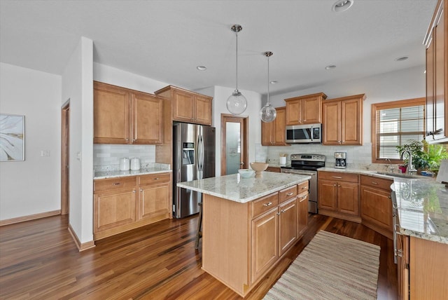 kitchen with stainless steel appliances, a sink, a center island, dark wood-style floors, and decorative light fixtures