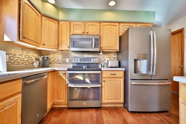 kitchen featuring hardwood / wood-style flooring, appliances with stainless steel finishes, tasteful backsplash, and light brown cabinets