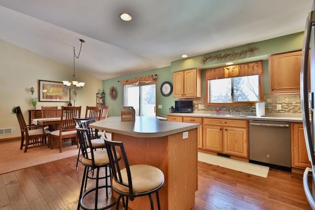 kitchen featuring lofted ceiling, hanging light fixtures, a center island, sink, and dishwasher