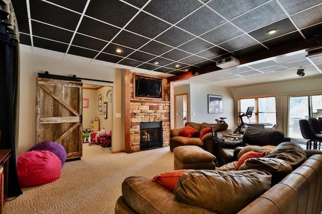 carpeted living room with a barn door and a stone fireplace