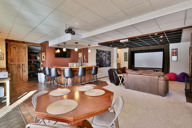 dining area featuring bar, carpet flooring, and a drop ceiling