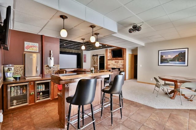 kitchen featuring a paneled ceiling, a barn door, a kitchen breakfast bar, and decorative light fixtures