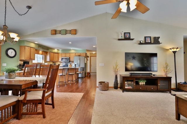 dining space featuring high vaulted ceiling, light hardwood / wood-style floors, and ceiling fan with notable chandelier