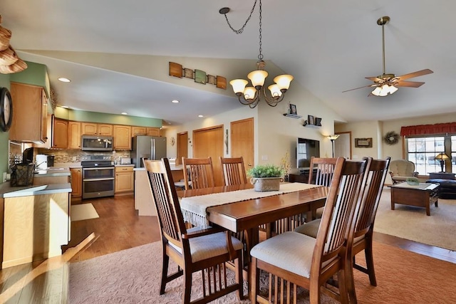 dining area featuring ceiling fan with notable chandelier, vaulted ceiling, and hardwood / wood-style floors