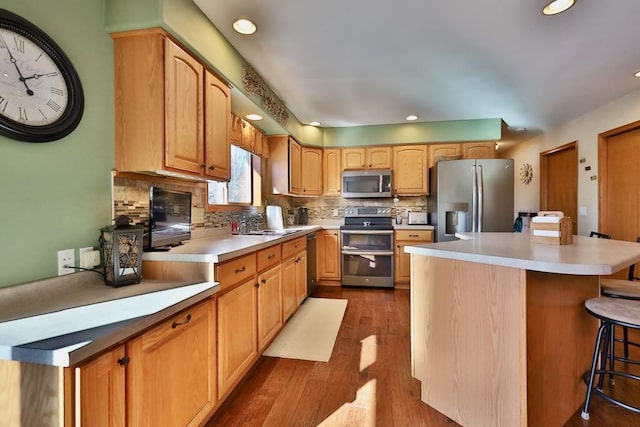 kitchen featuring backsplash, a kitchen island, light hardwood / wood-style floors, stainless steel appliances, and a breakfast bar area