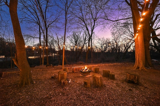 yard at dusk featuring an outdoor fire pit